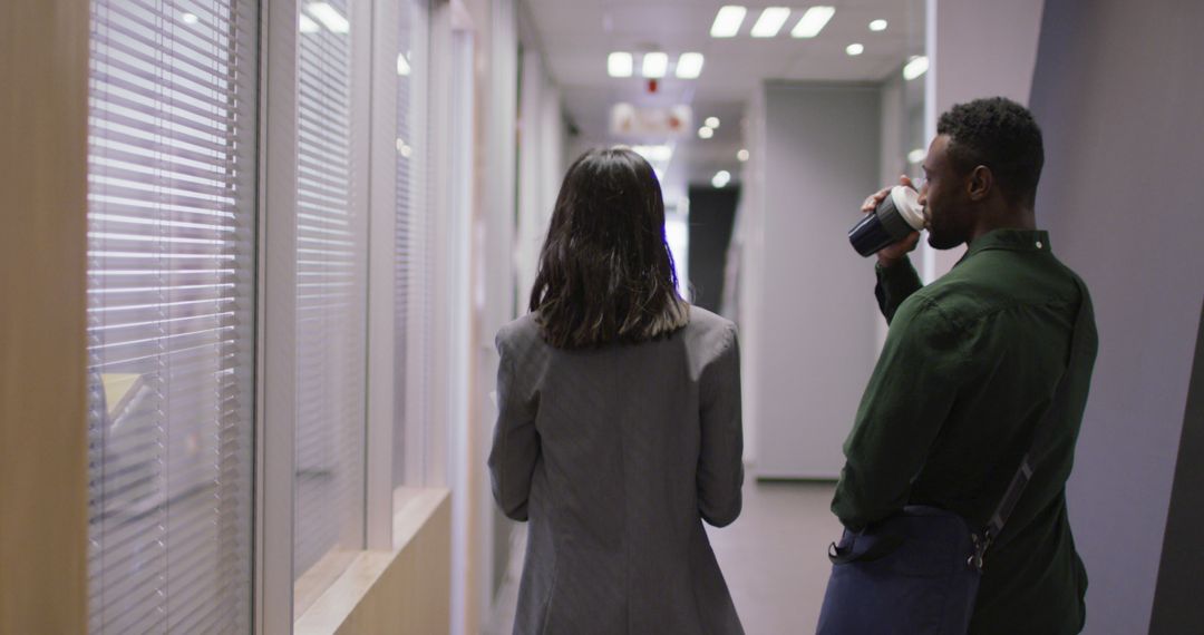 Colleagues Conversing in Office Corridor with Coffee