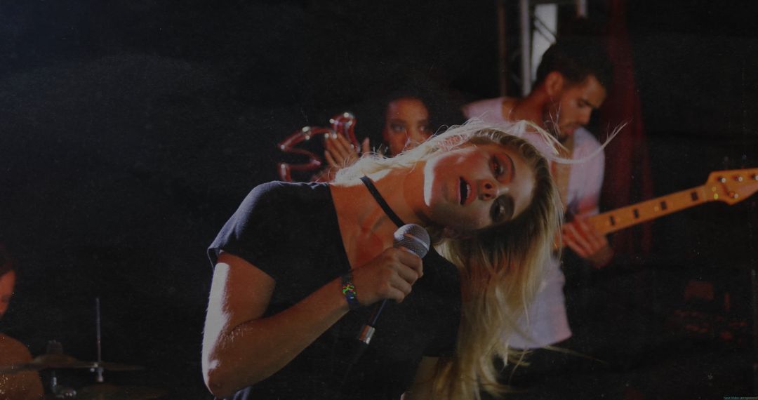 Blonde Vocalist Performing with Band on Stage in Concert