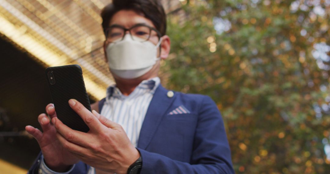 Businessman Wearing Face Mask Checking Smartphone Outdoors - Free Images, Stock Photos and Pictures on Pikwizard.com