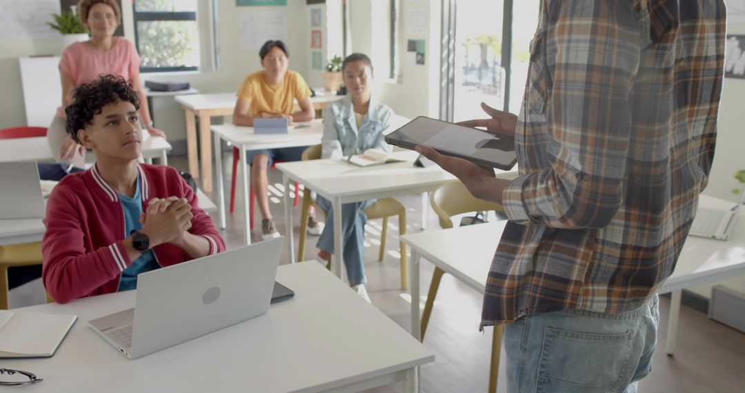 Instructor presenting with tablet to attentive students in interactive classroom lesson