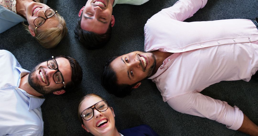 Diverse Coworkers Lying on Carpet in Office Smiling at Camera - Free Images, Stock Photos and Pictures on Pikwizard.com