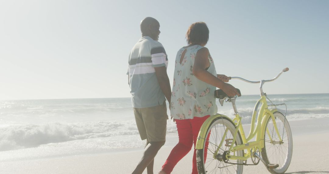 Couple Walking Along Beach with Bicycle on Sunny Day - Free Images, Stock Photos and Pictures on Pikwizard.com