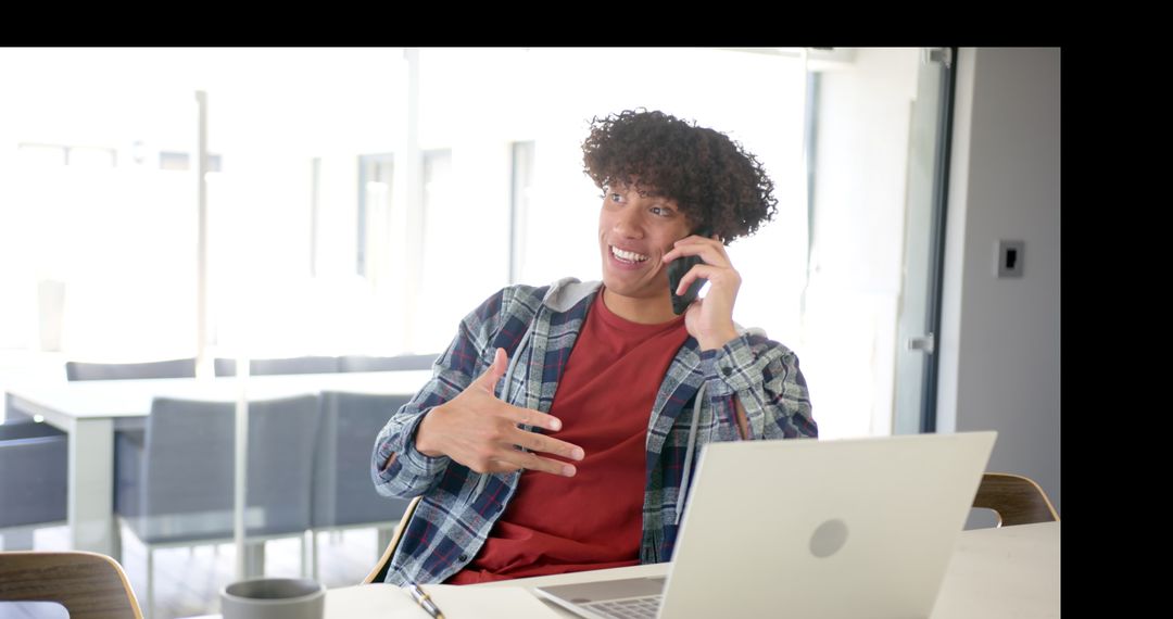 Young Adult Multi-tasking with Laptop and Phone in Home Kitchen