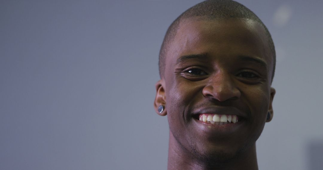 Young Man Smiling with Ear Studs on Grey Background - Free Images, Stock Photos and Pictures on Pikwizard.com