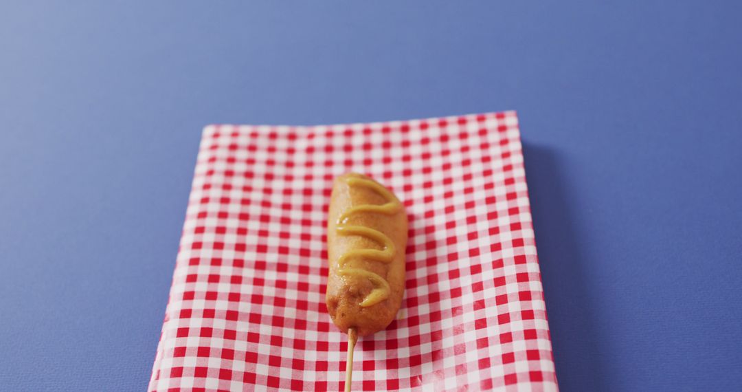 Tasty Corn Dog on Red Checkered Napkin with Mustard Drizzle