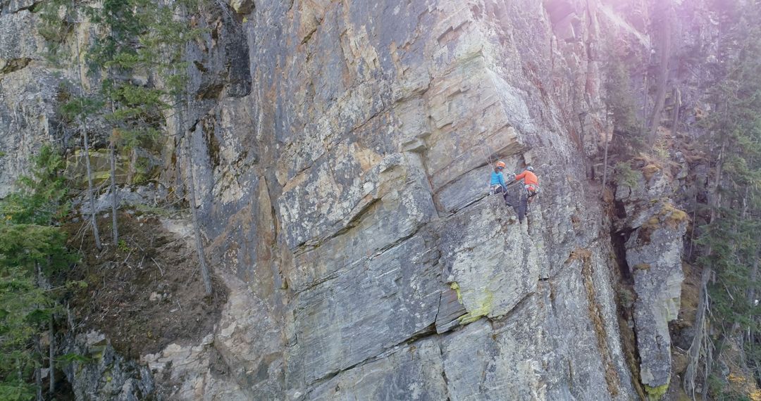 Caucasian Couple Rock Climbing Steep Cliff with Copy Space