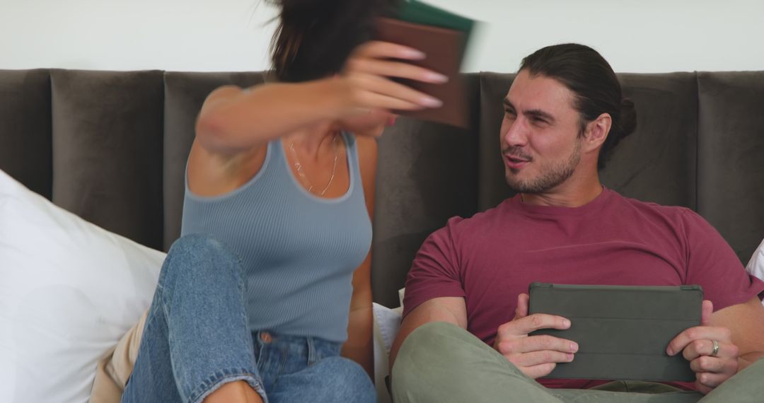 Playful Couple with Tablet Discussing Plans in Bed