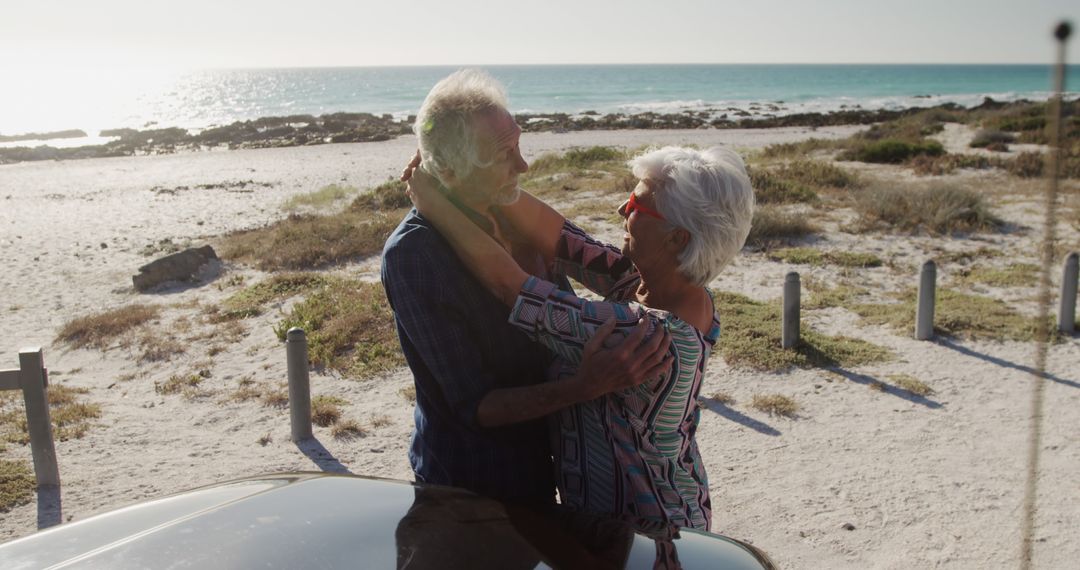 Senior Couple Embracing at Beach During Sunny Day - Free Images, Stock Photos and Pictures on Pikwizard.com