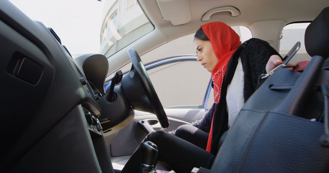 Woman wearing red headscarf getting into her car holding a black handbag - Free Images, Stock Photos and Pictures on Pikwizard.com