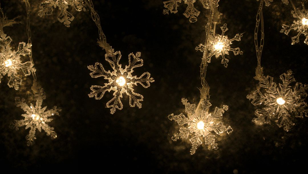 Warm Golden Snowflake String Lights Hanging Against Dark Night Background, Festive Bokeh Glow