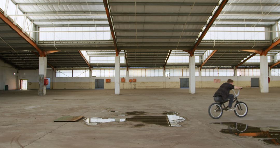 Young Man Riding BMX Bike in Spacious Abandoned Warehouse - Free Images, Stock Photos and Pictures on Pikwizard.com