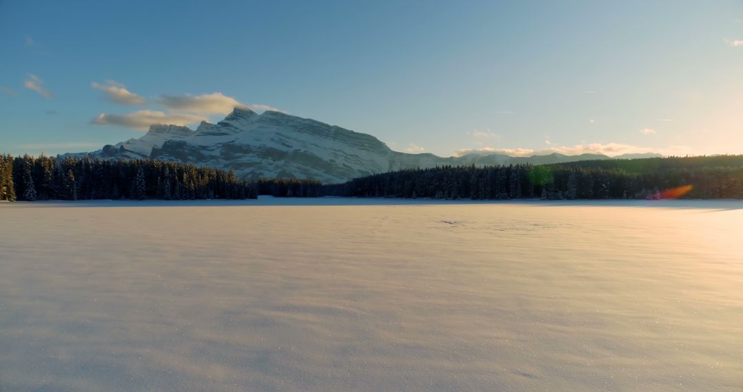 A tranquil winter scene displays a snowy field and mountains under a clear sky with copy space. - Free Images, Stock Photos and Pictures on Pikwizard.com