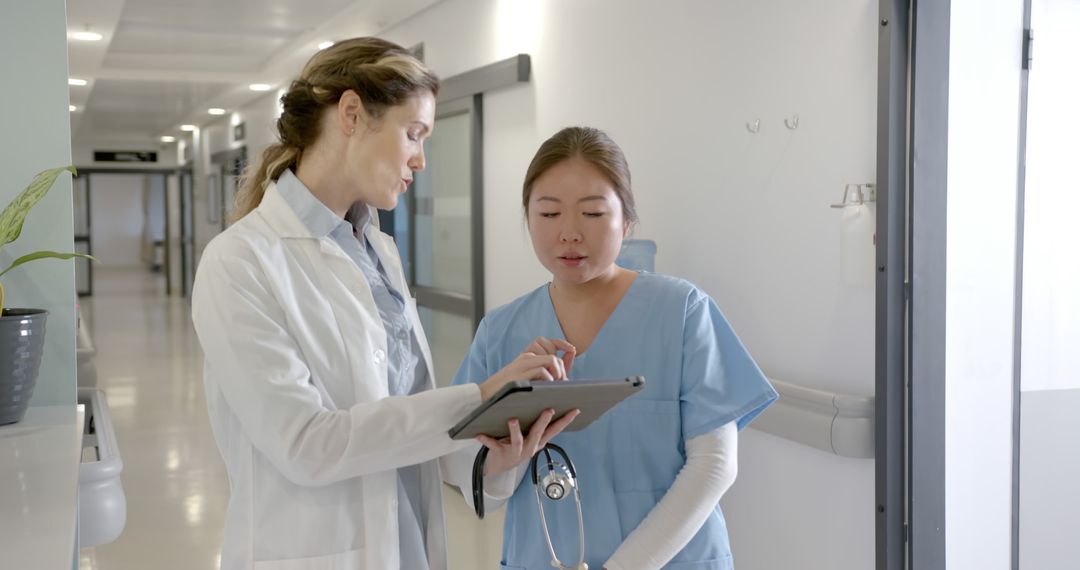 Doctor Discussing Patient Report with Nurse in Hospital Corridor - Free Images, Stock Photos and Pictures on Pikwizard.com