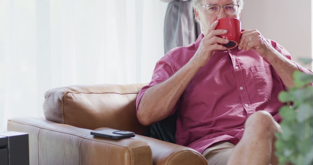 Elderly Man Relaxing on Sofa with Coffee Mug in Living Room - Free Images, Stock Photos and Pictures on Pikwizard.com