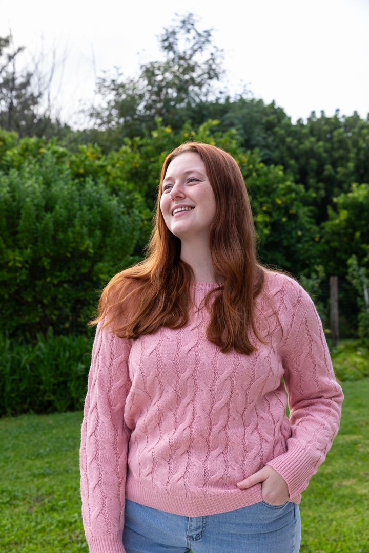 Smiling Woman Enjoying a Serene Garden in Casual Pink Sweater