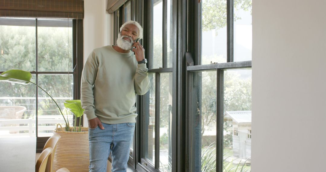 Senior Man Talking On Smartphone In Bright Modern Home