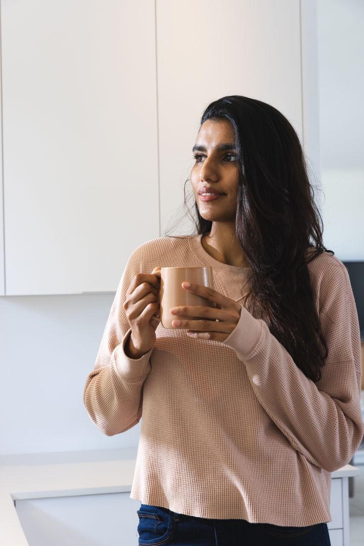 Contemplative Woman Holding Mug in Minimalist Kitchen