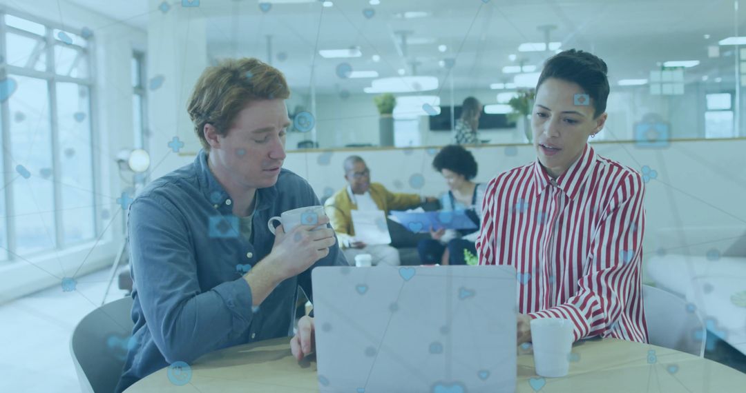 Diverse Professionals Discussing Over Laptop in Modern Office