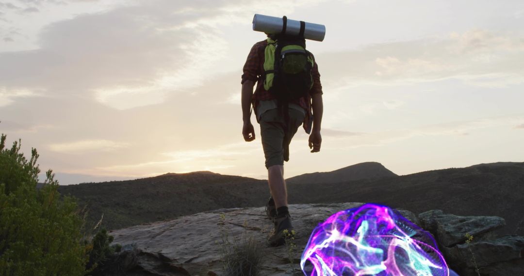 Hiker with Backpack at Sunset and Mysterious Glowing Orb