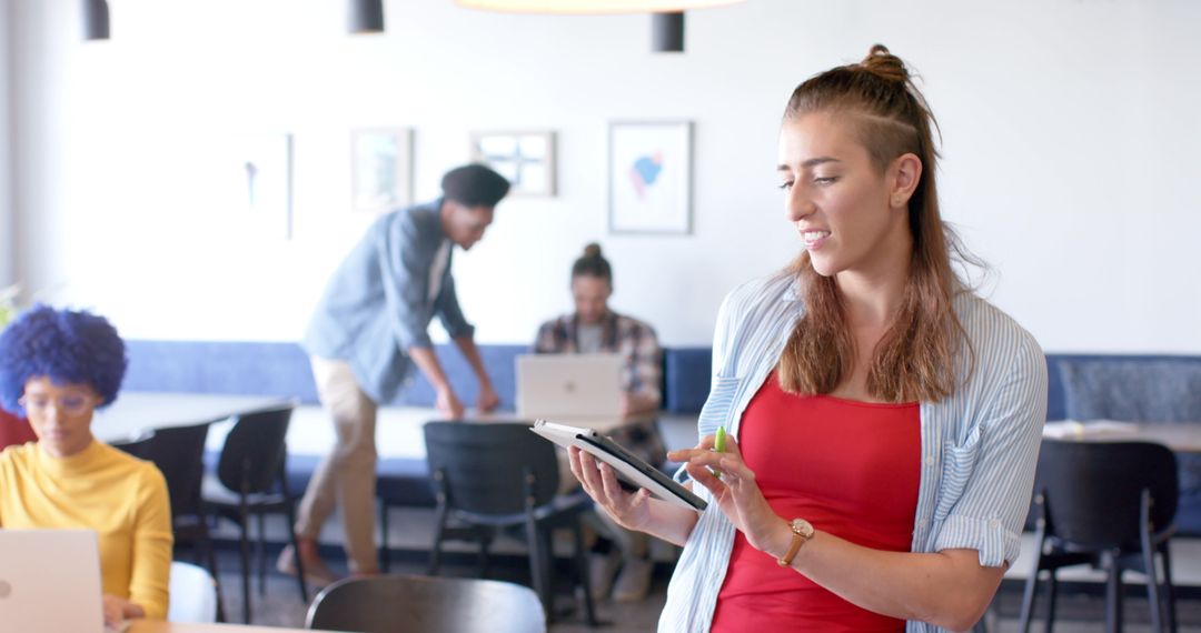Young Professional Reviewing Data on Tablet in Collaborative Office Setting