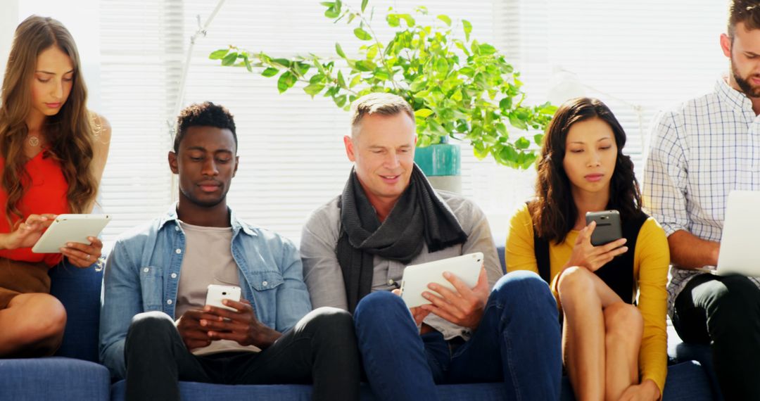 Diverse Group Engaged with Digital Devices in Modern Common Area