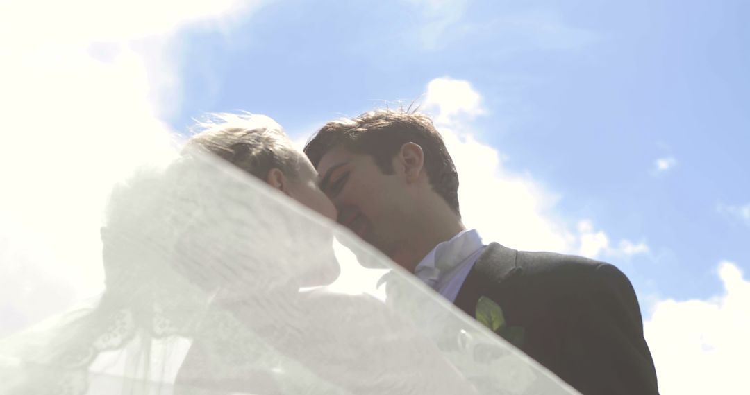 Bride and Groom Kissing in Sunlight Under Clear Blue Sky - Free Images, Stock Photos and Pictures on Pikwizard.com