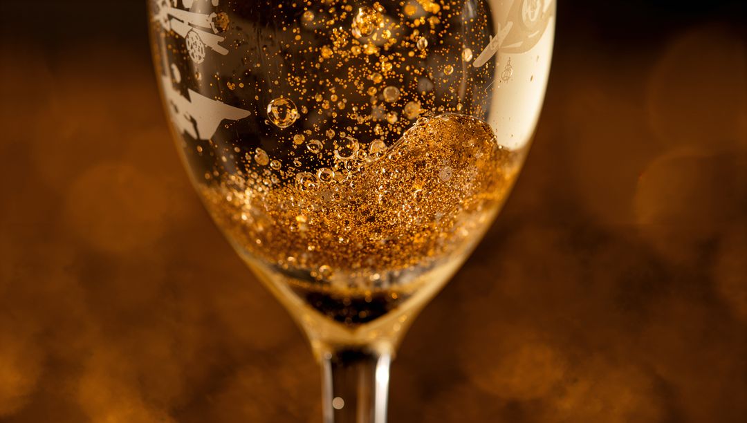 Golden effervescence in etched stem glass with glittering bubbles and warm bokeh