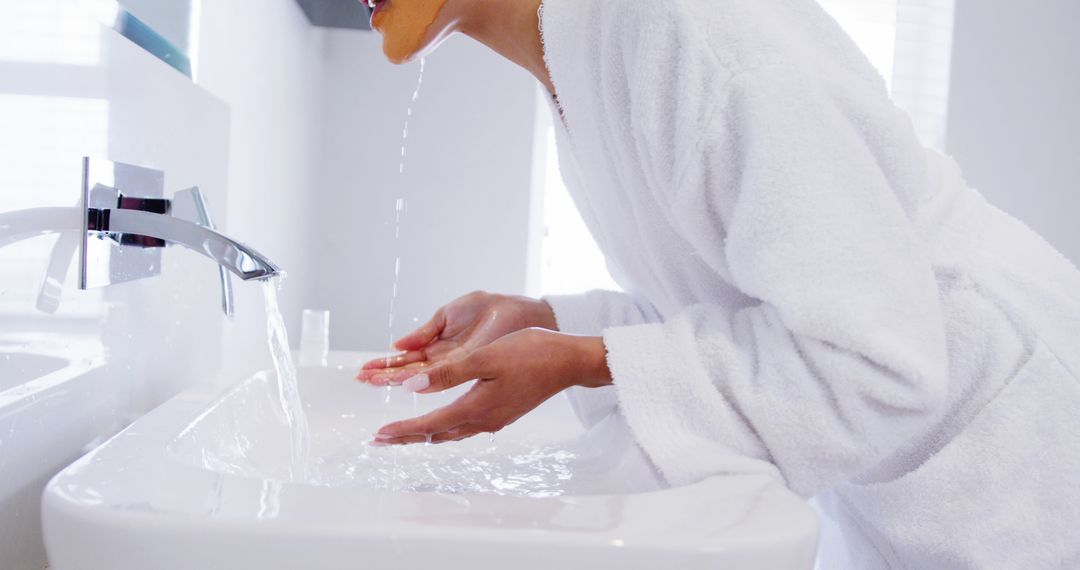 Person Washing Face by Sink with White Bathrobe - Free Images, Stock Photos and Pictures on Pikwizard.com