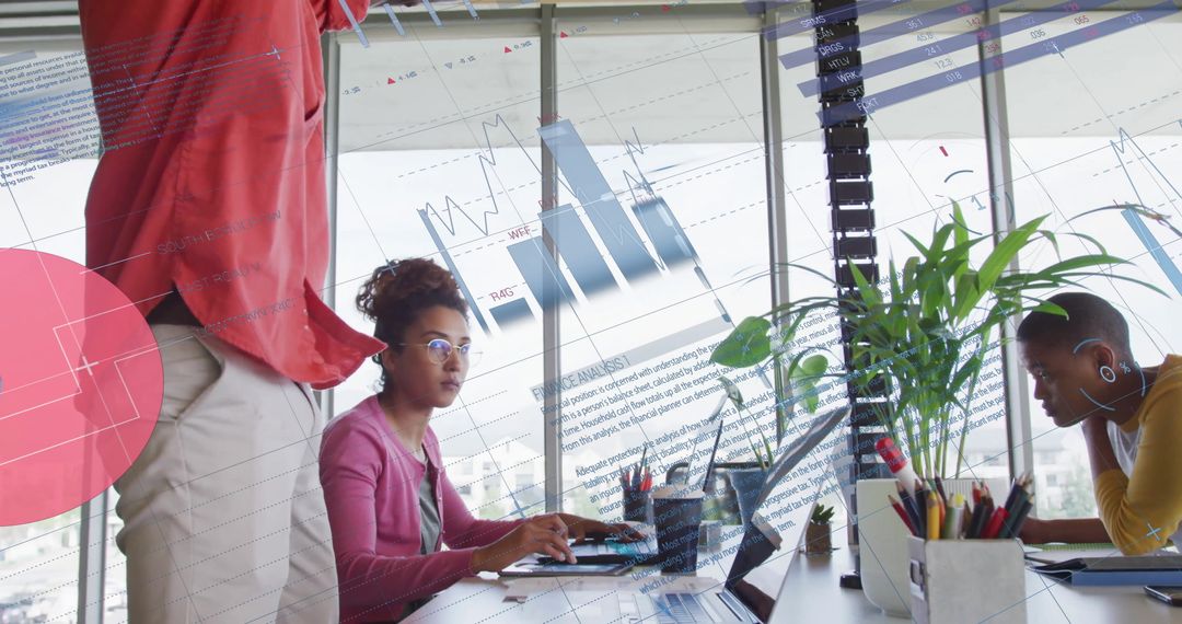 Diverse Team Analyzing Business Data on Laptops in Modern Office