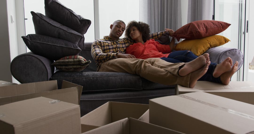 Happy Couple Relaxing on Couch with Moving Boxes at Home