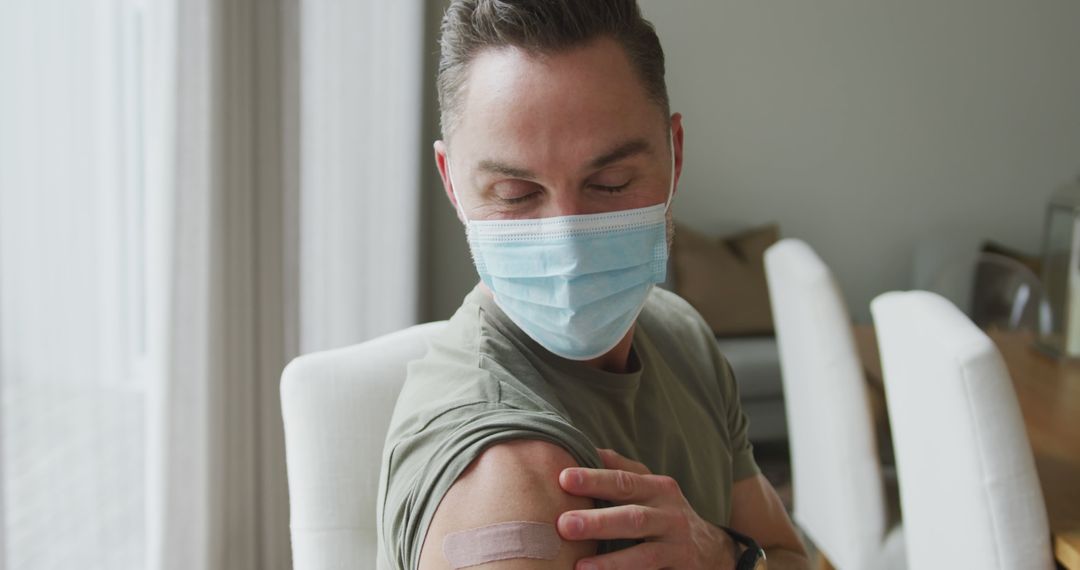 Man Wearing Face Mask Checking Injection Site on Arm - Free Images, Stock Photos and Pictures on Pikwizard.com