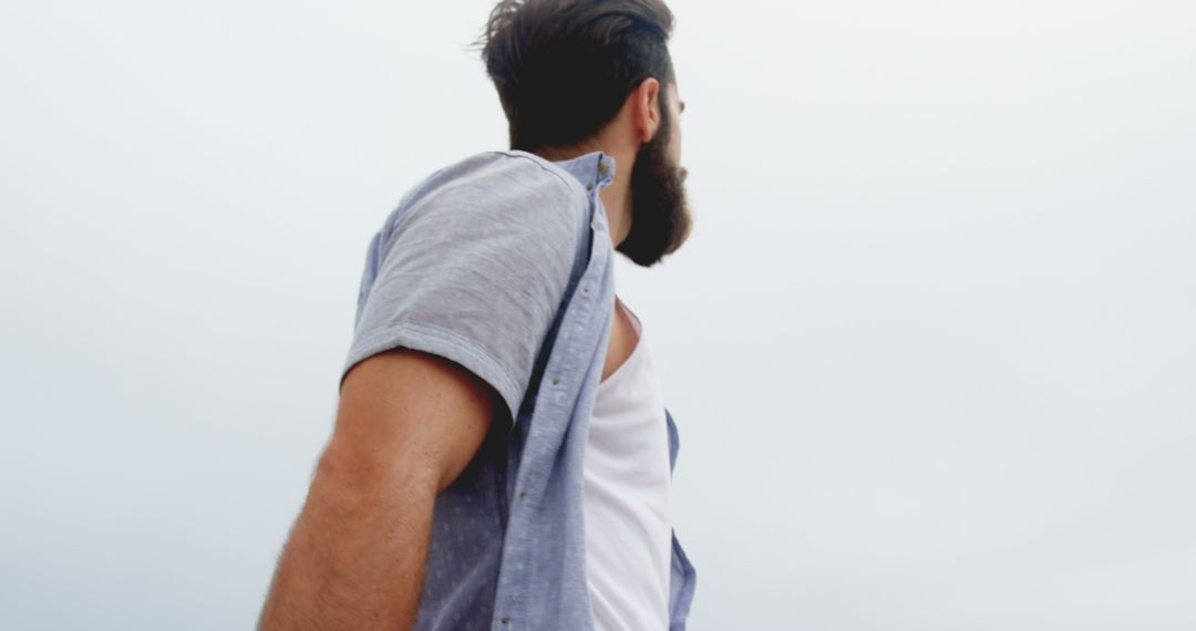 Man Gazing at Sky with Windswept Hair and Casual Outfit
