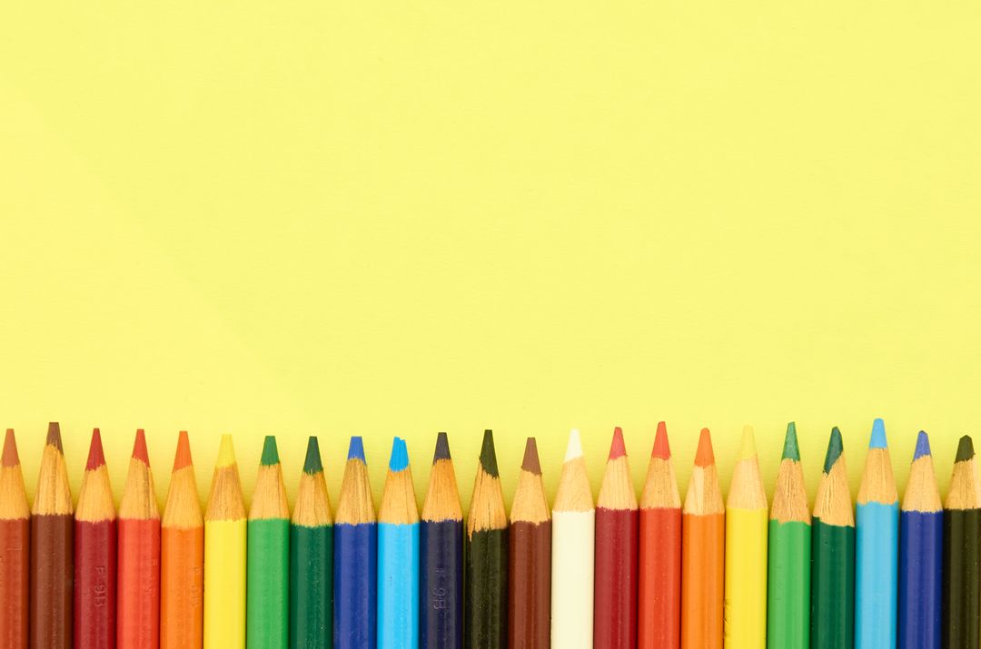 Rainbow Colored Pencils Lining Bottom Edge on Bright Yellow Background