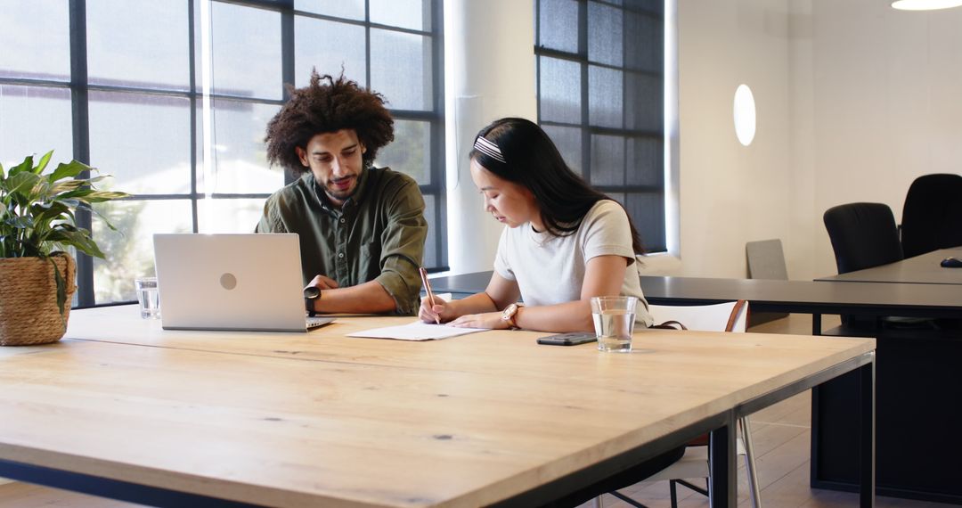 Diverse Team Collaborates Over Work Documents in Modern Office