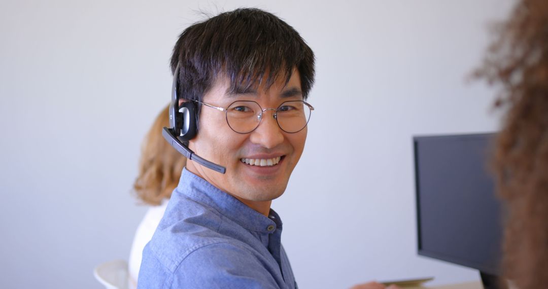 Smiling Asian Customer Service Agent with Headset in Modern Office