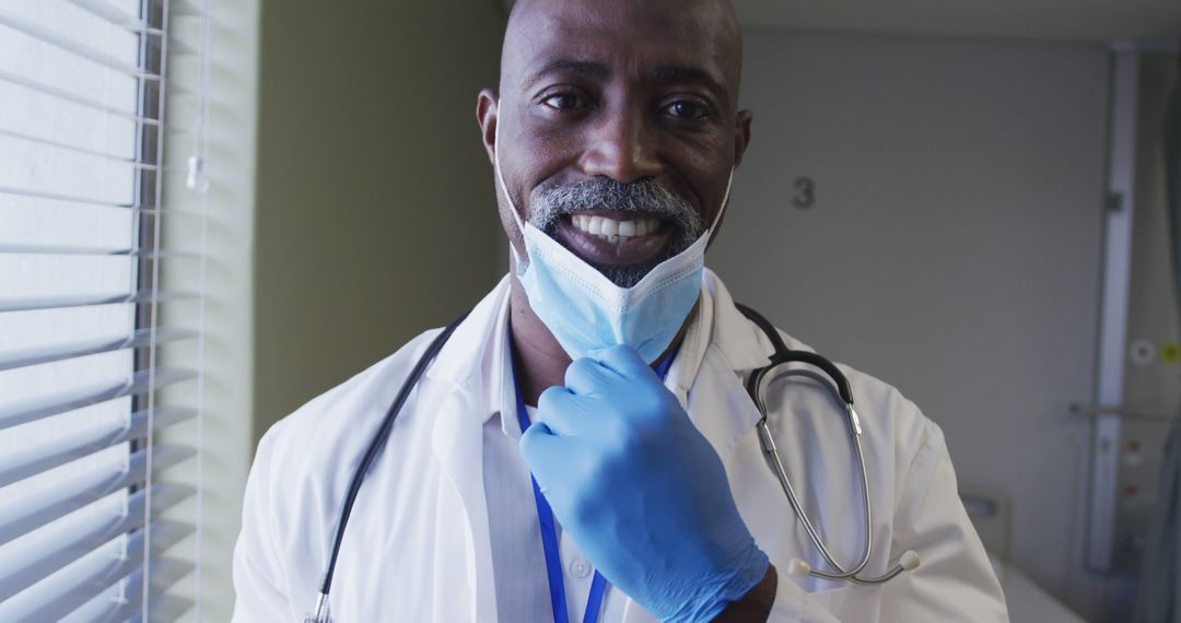 Portrait of smiling african american male doctor wearing face mask standing in hospital room - Free Images, Stock Photos and Pictures on Pikwizard.com
