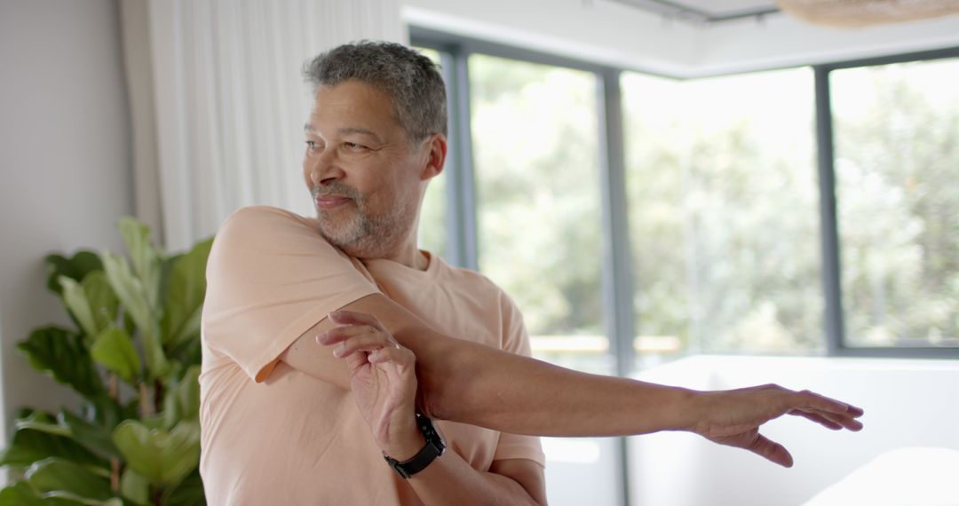 Senior Man Stretching Arm in Bright Room - Free Images, Stock Photos and Pictures on Pikwizard.com