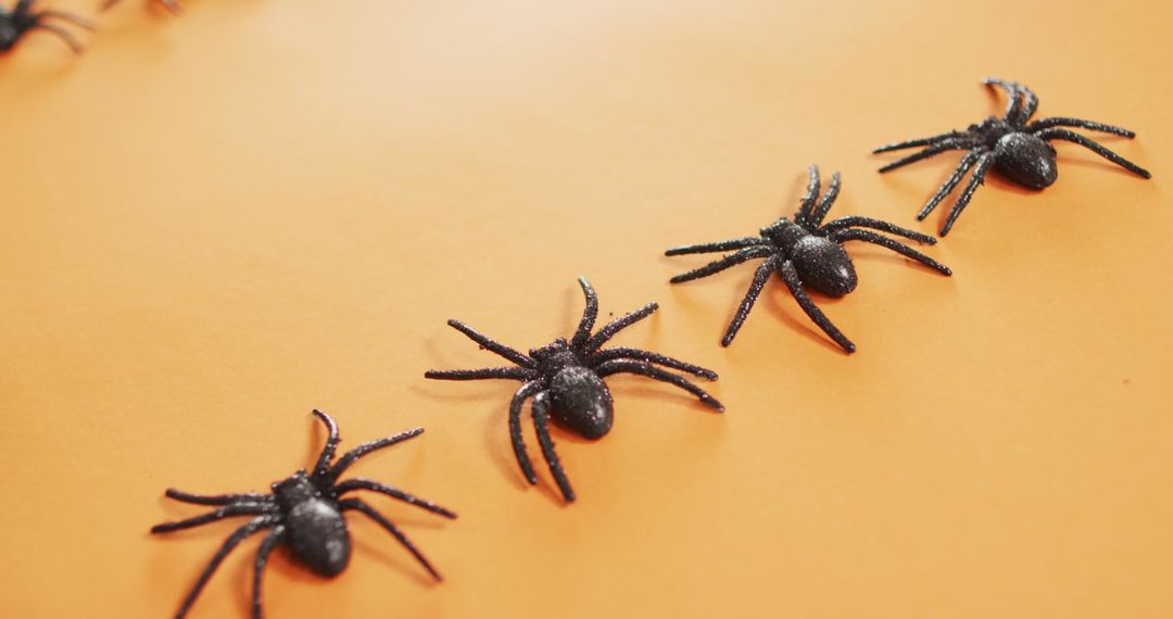 Close up of multiple spider toys with copy space against orange background - Free Images, Stock Photos and Pictures on Pikwizard.com