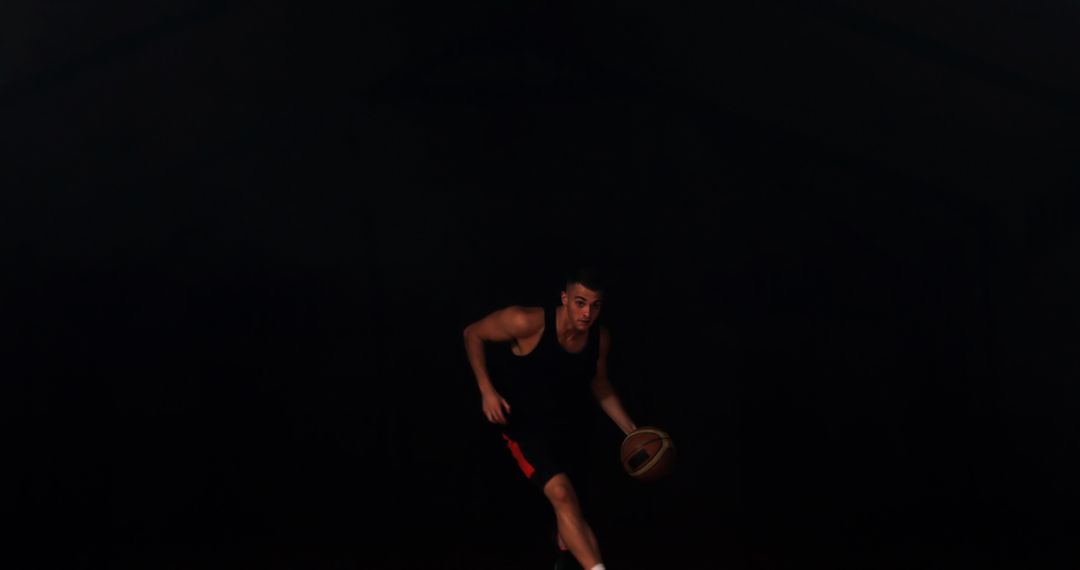 Focused Athlete Dribbling Basketball in Dark Court - Free Images, Stock Photos and Pictures on Pikwizard.com