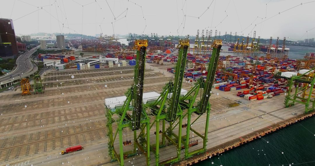 Green gantry cranes towering above busy container terminal with colorful containers