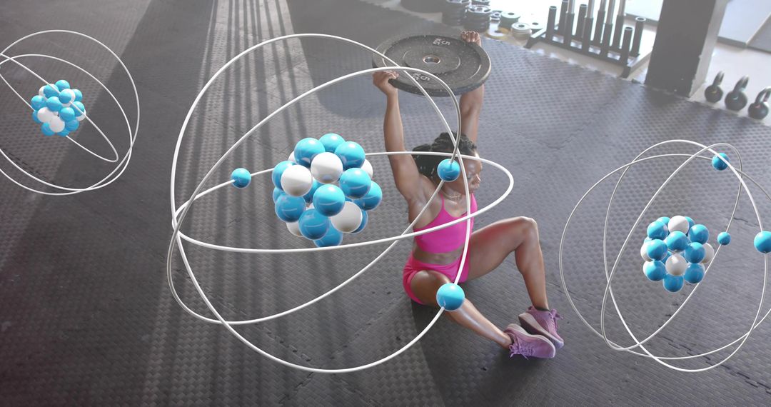 Woman pressing weight plate overhead while sitting on gym floor with orbit atom graphics