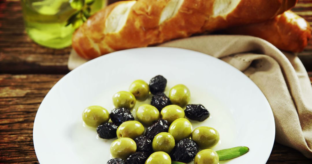 Assorted Olives on White Plate with Baguette in Background - Free Images, Stock Photos and Pictures on Pikwizard.com