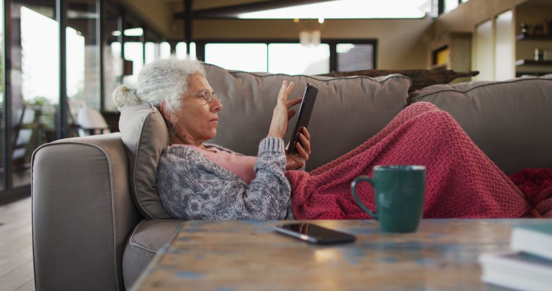 Senior Woman Relaxing on Couch with Tablet in Cozy Living Room - Free Images, Stock Photos and Pictures on Pikwizard.com