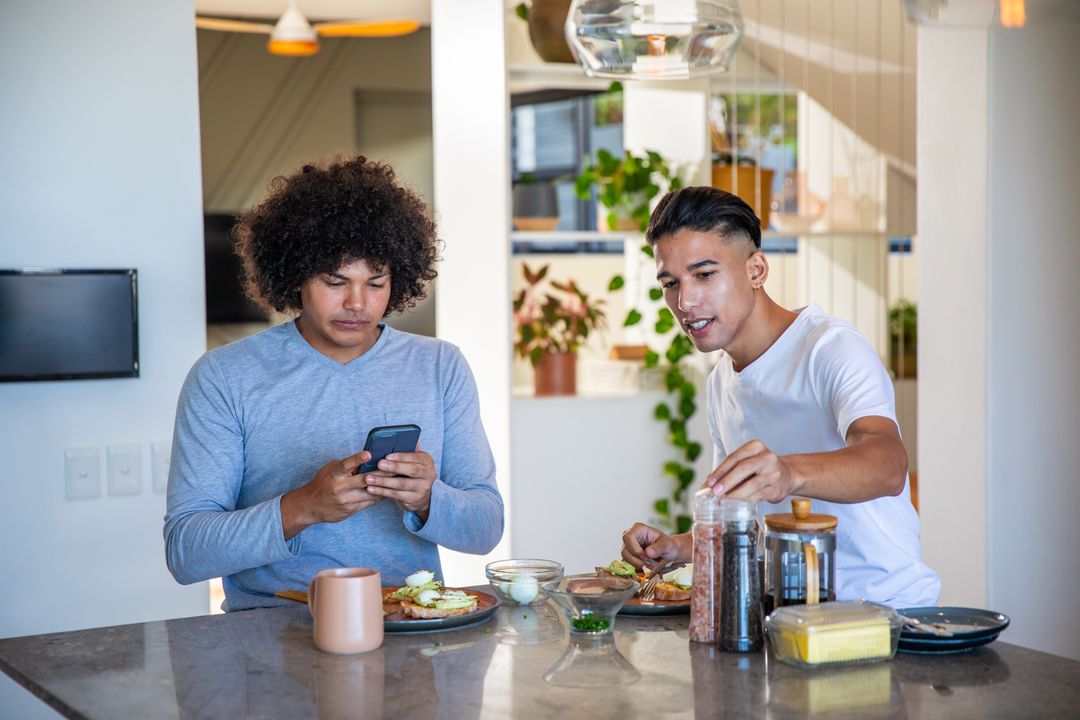 Two Friends Sharing Breakfast While Using Smartphone