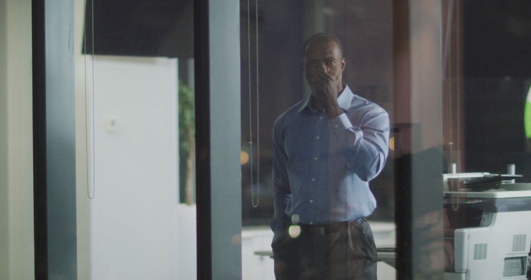 Pensive Businessman Stands Behind Office Glass During Late Hours - Free Images, Stock Photos and Pictures on Pikwizard.com