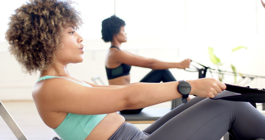 Women Practicing Pilates on Rowing Machines with Intense Focus