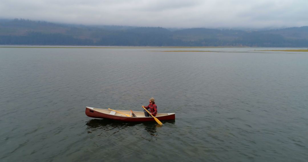 Person Canoeing on Calm Lake with Misty Mountains in Background - Free Images, Stock Photos and Pictures on Pikwizard.com