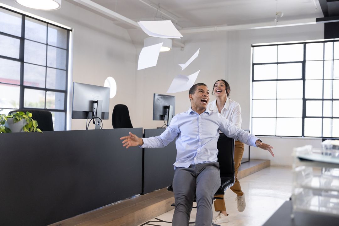 Office Workers Enjoying Chair Ride in Open Workspace