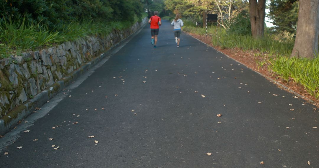 Two Men Running on Paved Path Through Forested Area - Free Images, Stock Photos and Pictures on Pikwizard.com