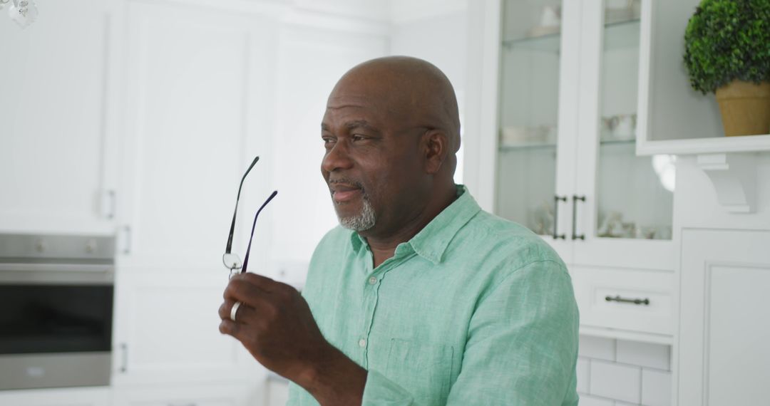 Smiling Senior African American Man Holding Glasses in Kitchen - Free Images, Stock Photos and Pictures on Pikwizard.com